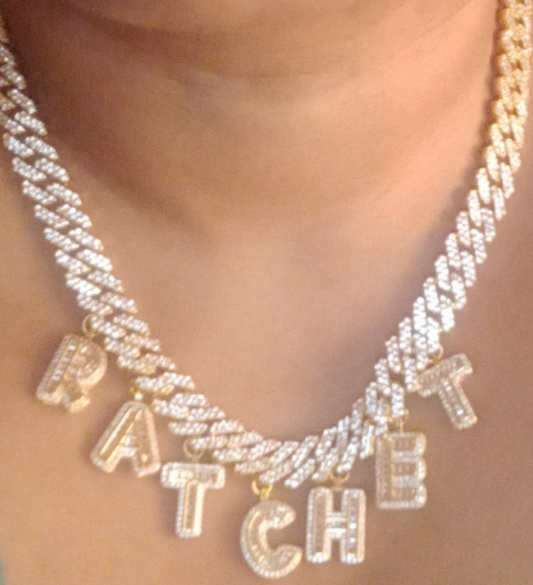 Gold LiNK CHAiN worn around a womans neck WiTH charms that spell the letters RATCHET